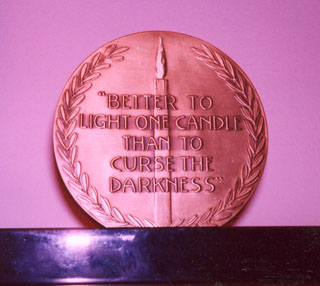 The back of the Christopher Medal contains the quote by Eleanor Roosevelt, 'It is better to light one candle than to curse the darkness.'